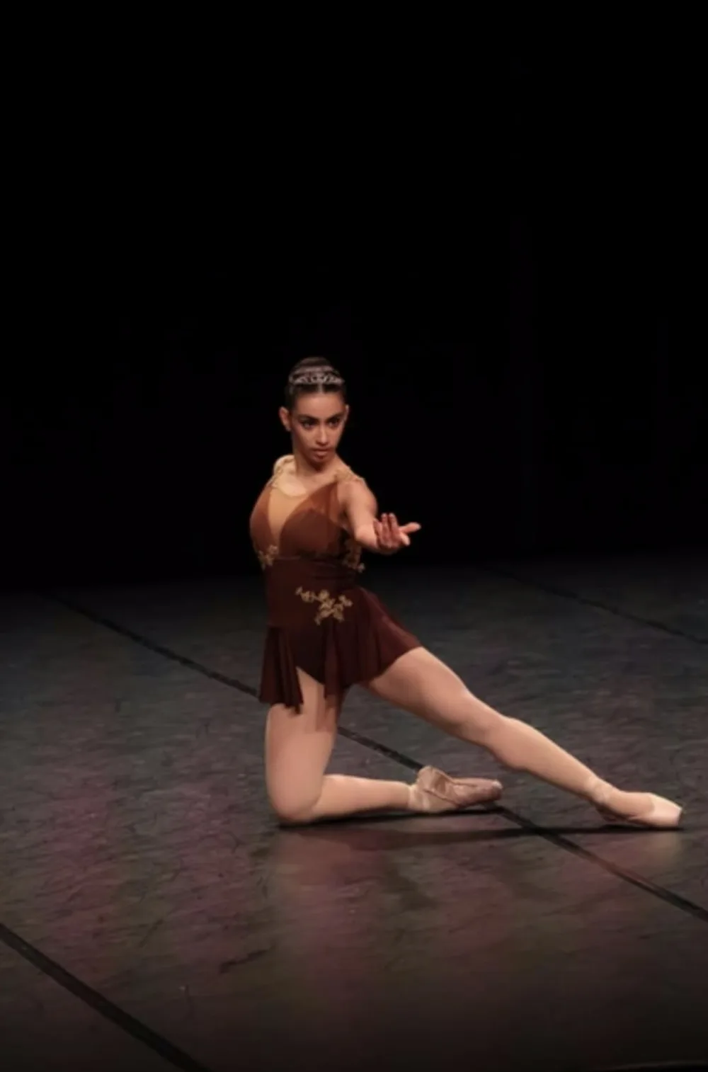 Danseuse sur scène portant un costume brun créé sur mesure