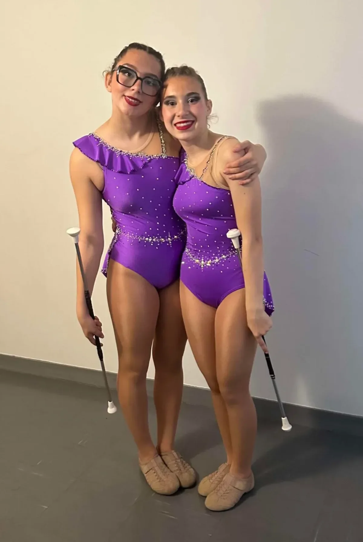 Deux twirleuses portant des justaucorps violets créés sur mesure avec strass